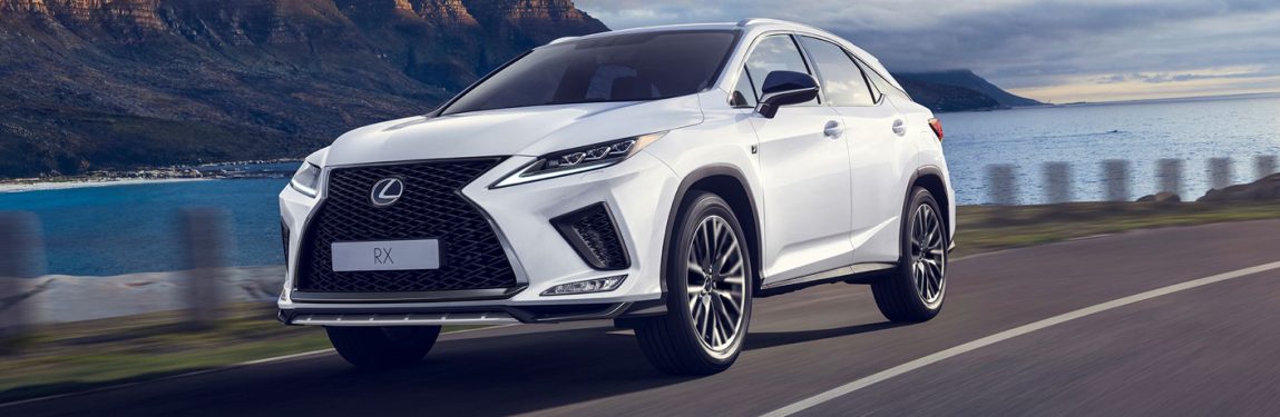 White 2020 Lexus RX drives up a coastal highway looking powerful.