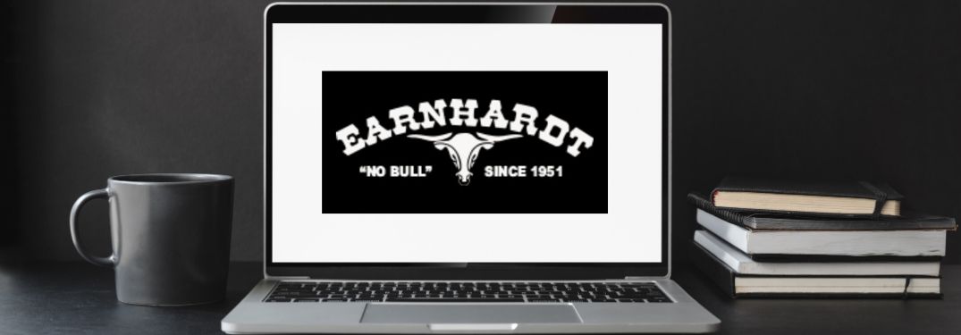 Laptop, Coffee Cup and Notebooks on a Desk with Black and White Earnhardt Bull Logo on the Laptop Screen