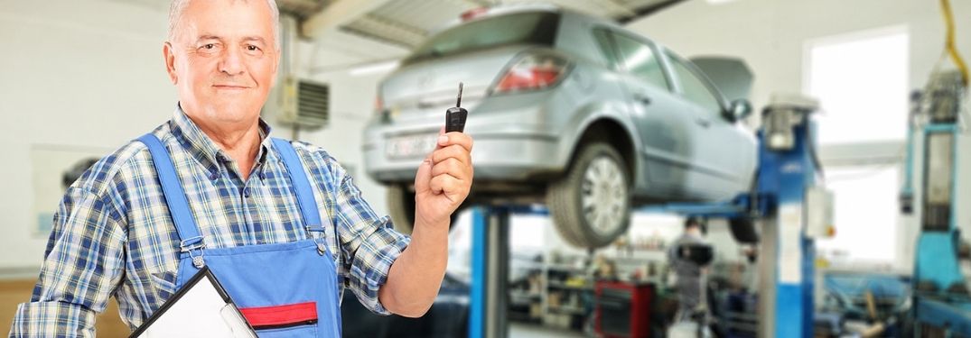 Mechanic Holding Up Car Key in a Garage