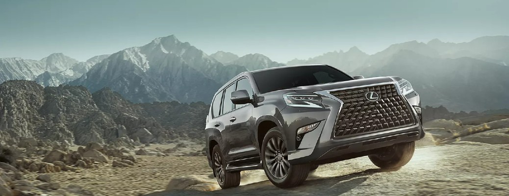 A 2022 Lexus GX driving offroad in the mountains, with snowcapped mountains in the distance