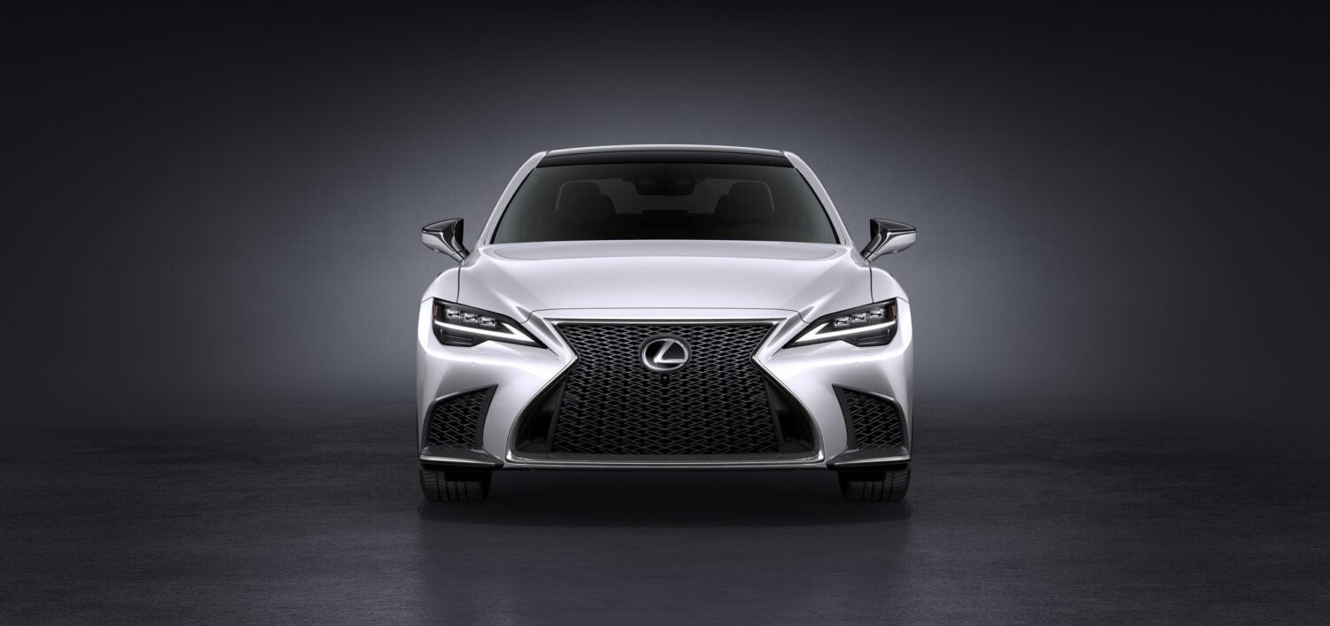 A white 2026 Lexus LS in Phoenix is parked facing the viewer in a dark grey showroom.