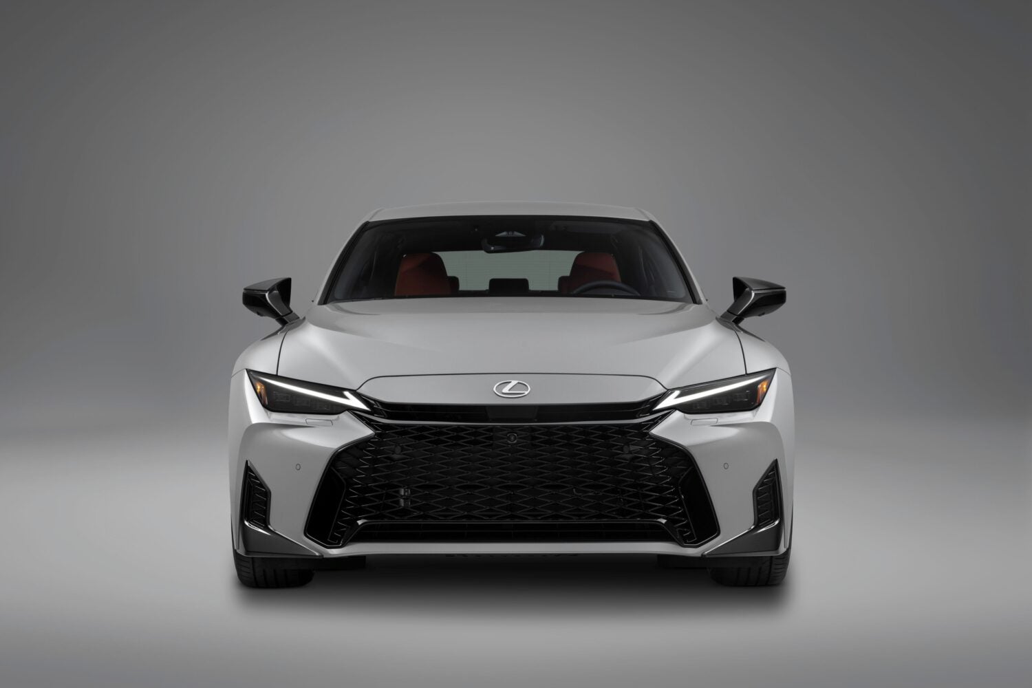 A silver new Lexus IS in Phoenix is parked facing the viewer in a white showroom.