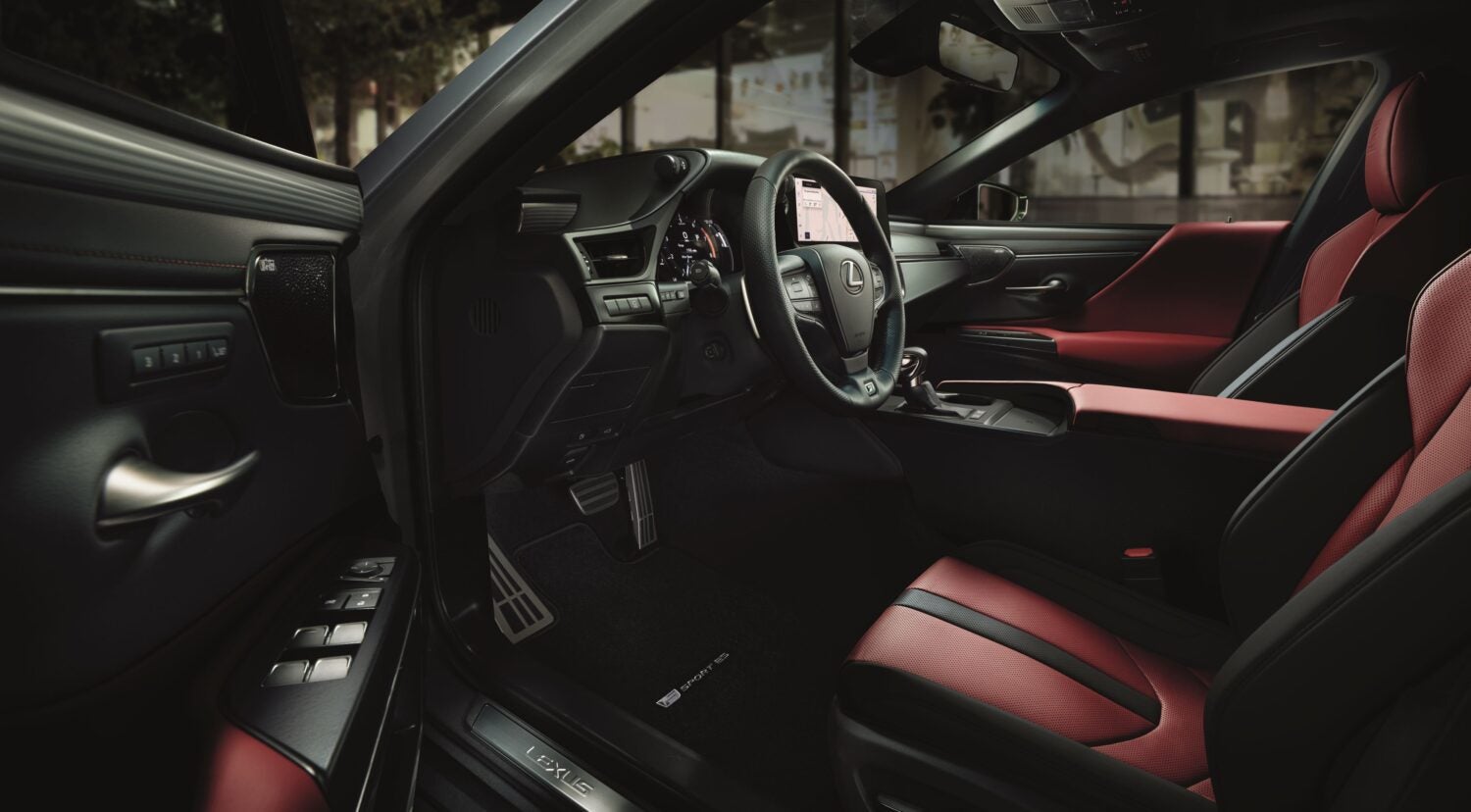 An interior shot of a Lexus ES, highlighting the driver's side. The seats feature a striking black and red leather design, and the dashboard is sleek and modern with various controls and a central display screen.