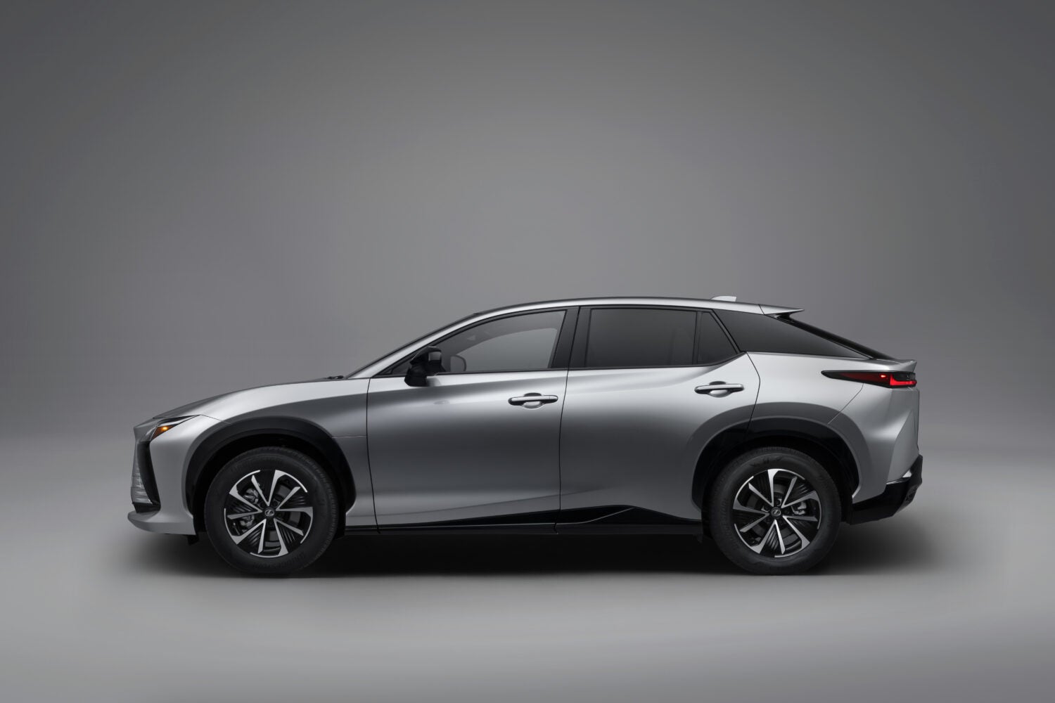 A silver new Lexus RZ 350e in Phoenix is parked facing left in a grey showroom.