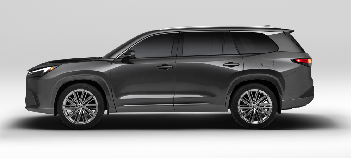 Front-three-quarter view of a black Lexus NX SUV driving on a desert highway with hills and a blue sky in the background.