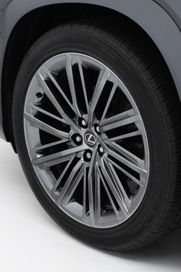 black Lexus NX SUV driving on a desert highway with hills in the background.