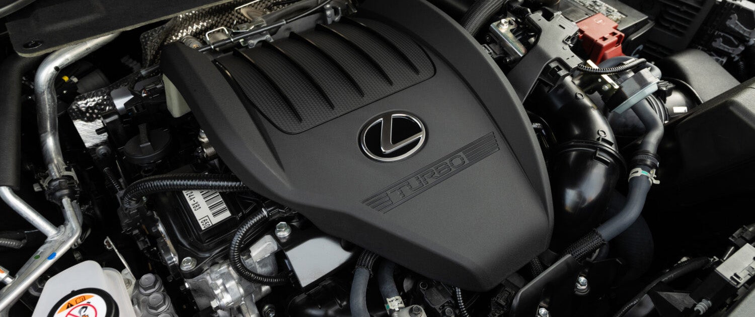 A black Lexus NX SUV driving on a highway through a desert landscape.